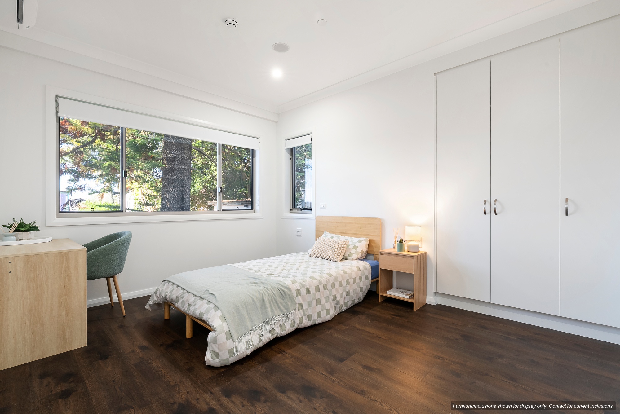 A minimalist bedroom in Narraweena with a single bed, bedside table, desk, chair, wood flooring, large window, and built-in wardrobes—perfect for enjoying the relaxed lifestyle of Sydney’s Northern Beaches.