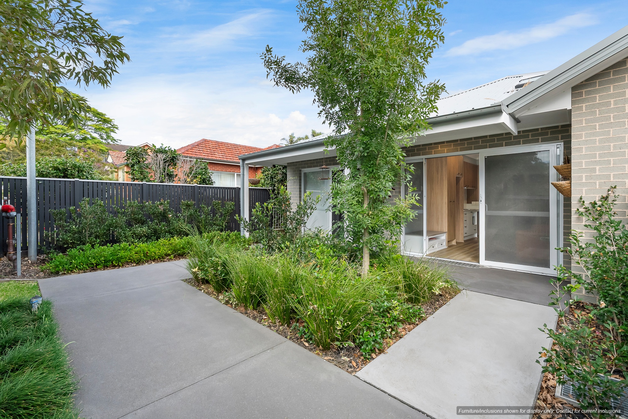 A modern single-story house in Pagewood with a light brick exterior, large windows, and a glass door, surrounded by a landscaped garden and concrete pathways in sought-after Inner South Sydney.
