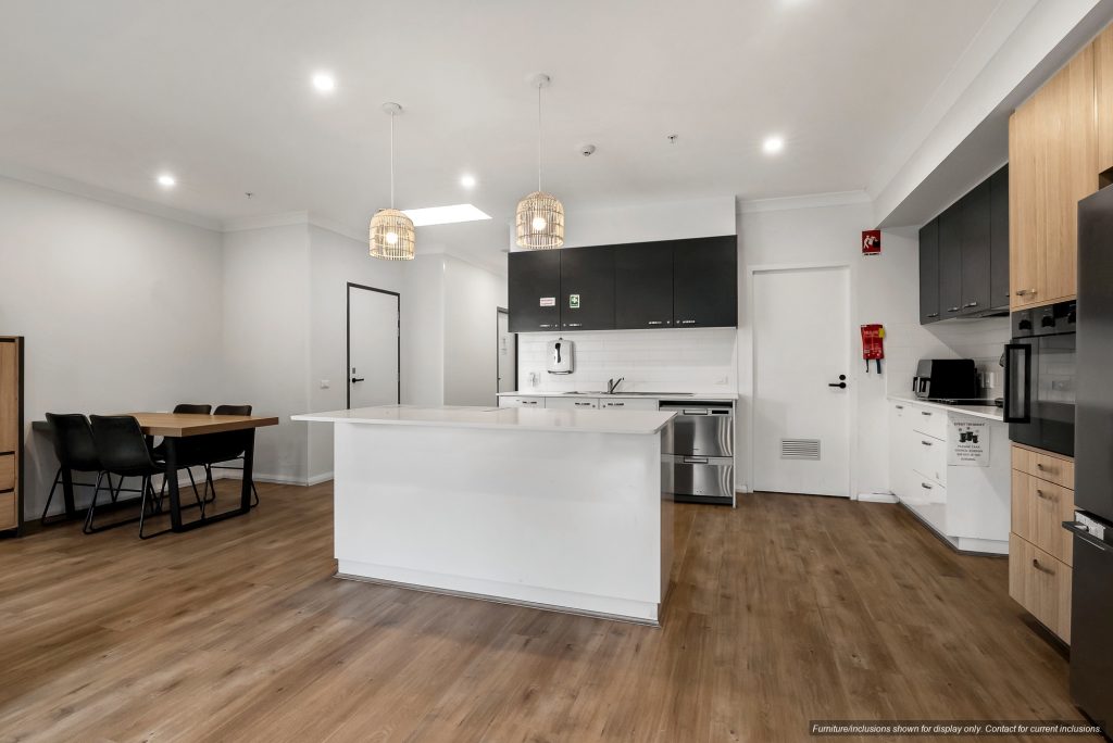 Modern kitchen with a central island, black and white cabinetry, pendant lights, dining table with chairs, and wood flooring in a stylish Concord home in Inner West Sydney.