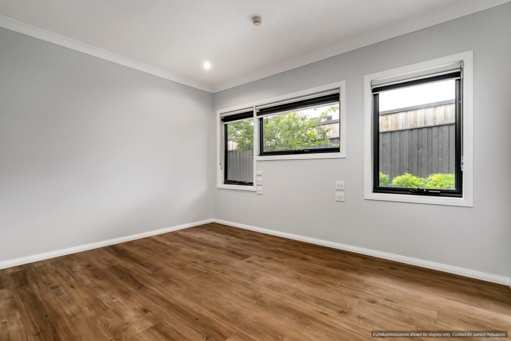 Empty room with light gray walls in Concord, Inner West Sydney, featuring three windows with black frames, white trim, wood flooring, and an outdoor view of a wooden fence and greenery. Listing reference: 10A.