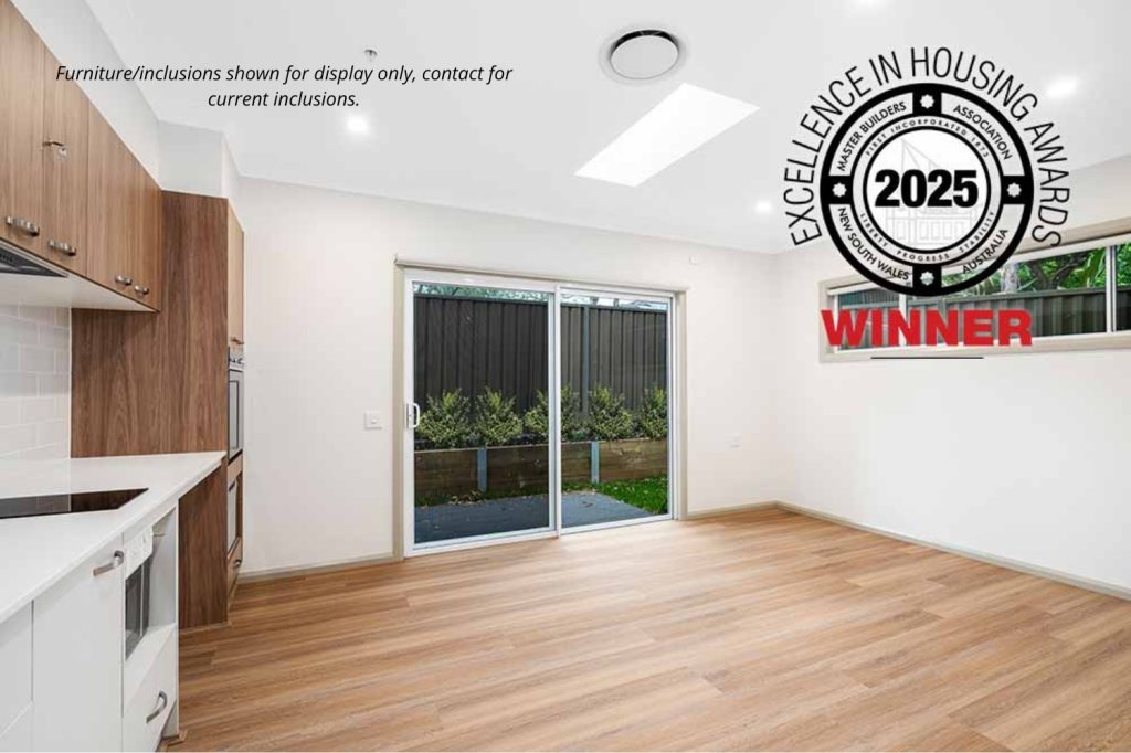Modern kitchen and living area with wood flooring, sliding glass doors, and a view of a fenced yard in Pendle Hill near Parramatta. "Excellence in Housing Awards 2025 Winner" badge appears in the top right corner.