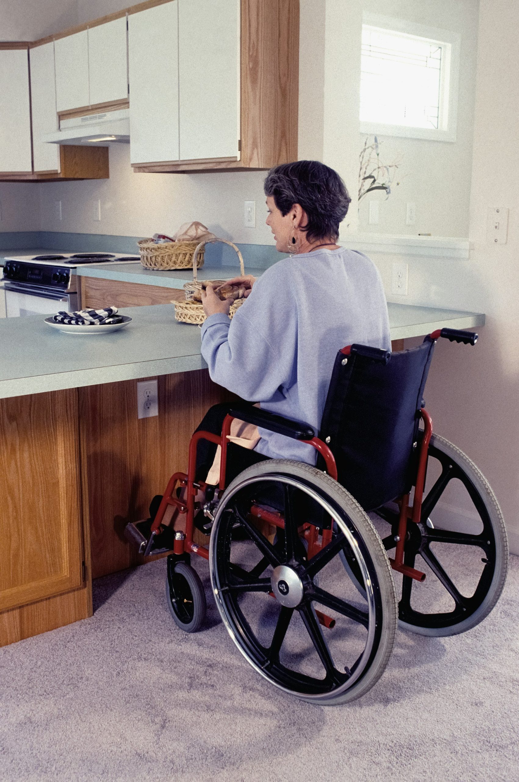 A person using a wheelchair in an accessible kitchen after moving into SDA