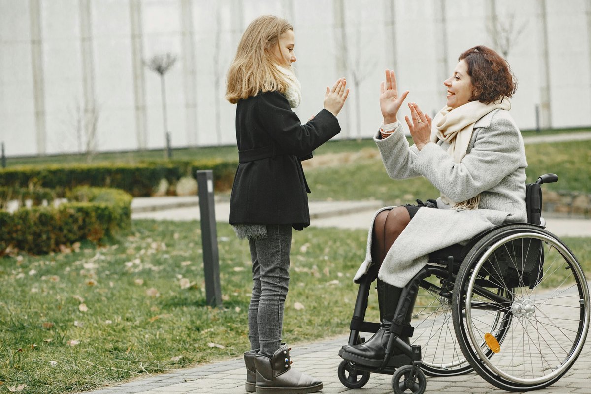 Family moment with child and parent in wheelchair outdoors, representing family connection in cerebral palsy housing