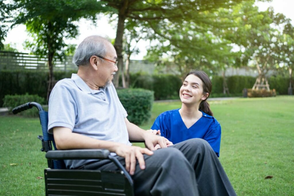 Old man on a wheelchair with his caregiver in the park