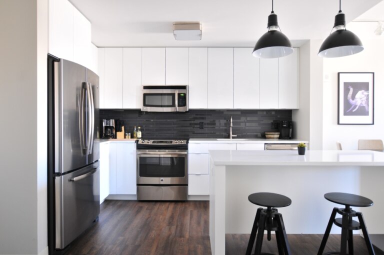 A white kitchen with black counter tops and stools NSW.