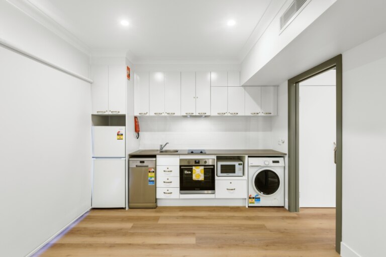 A small kitchen with a washer and dryer located in Maroubra, NSW.