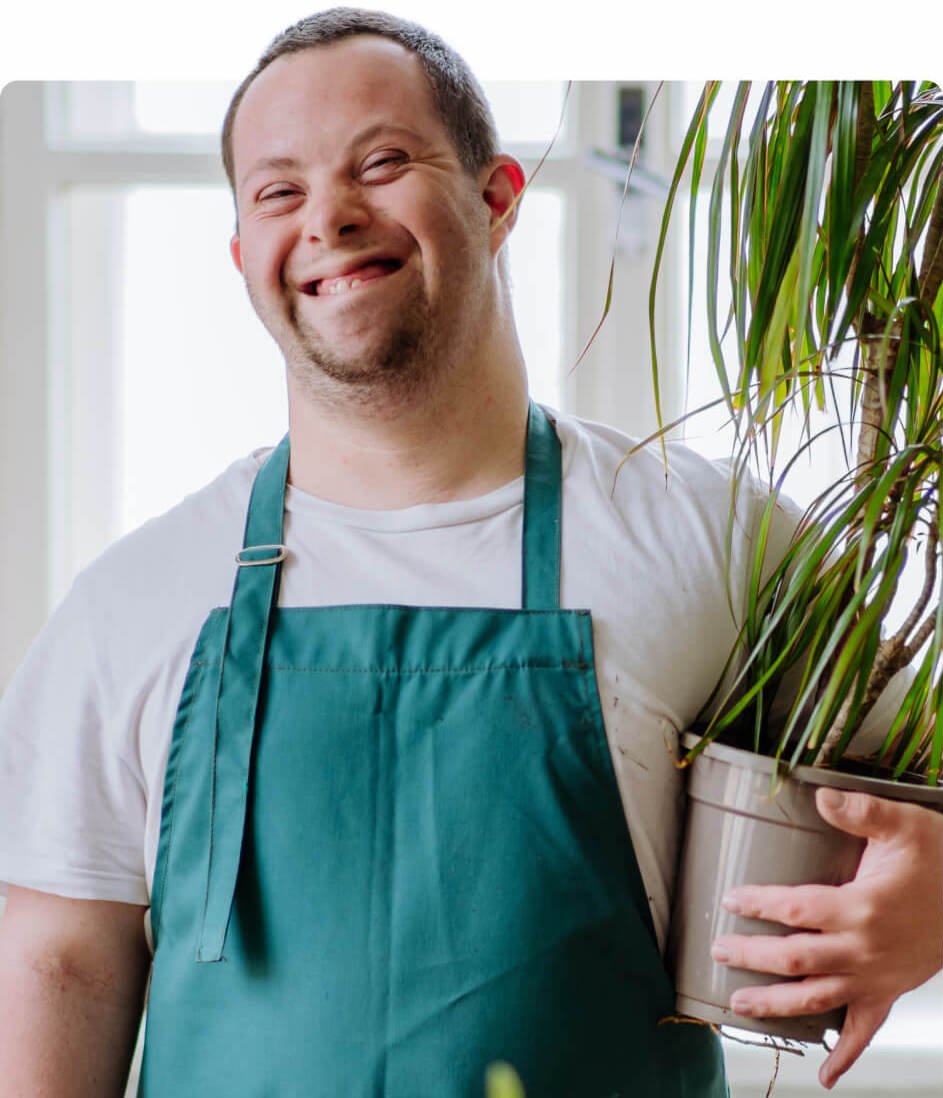 A man in an apron holding a potted plant.