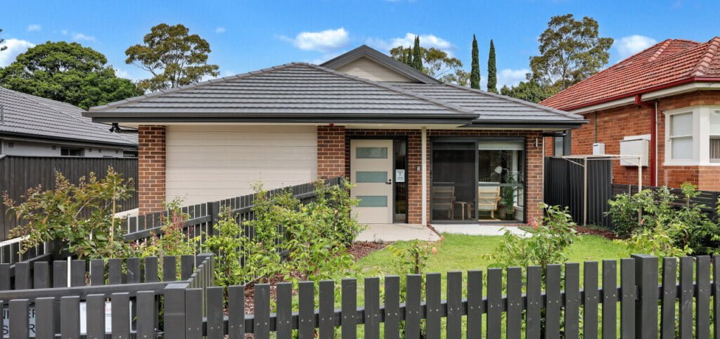 A small house with a fence in the backyard.