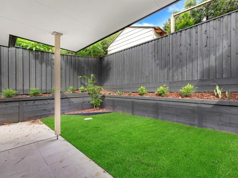 A backyard with grass and a wooden fence located in the inner west of Concord, NSW.