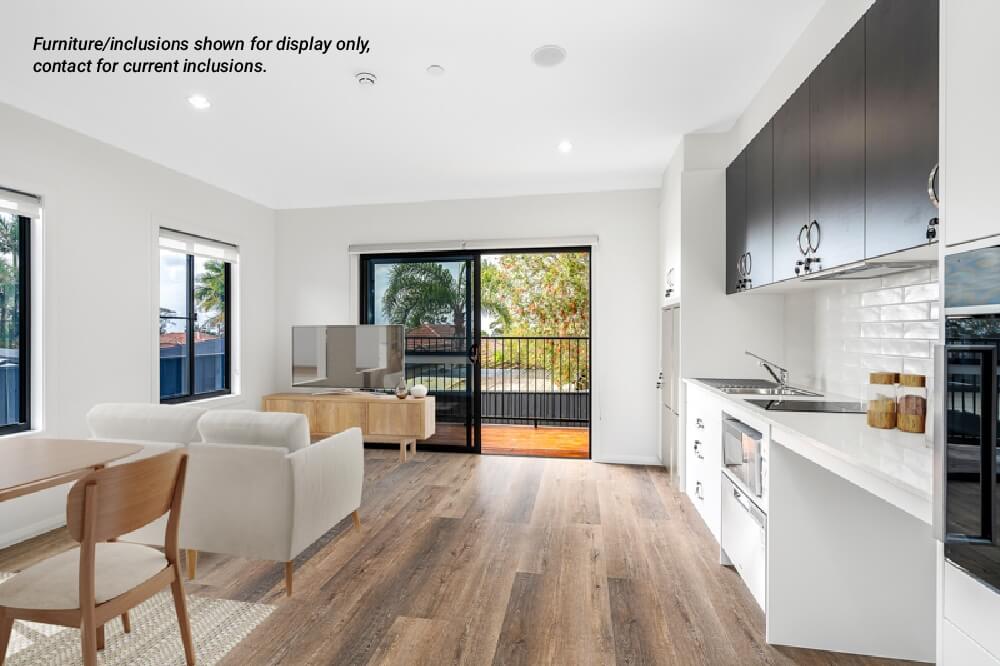 Modern open-plan living area in Narraweena with dining table, chairs, sofa, TV, kitchenette, and large glass doors opening to a balcony. Text in corner notes furnishings are for display only. Enjoy relaxed Northern Beaches living near Sydney.