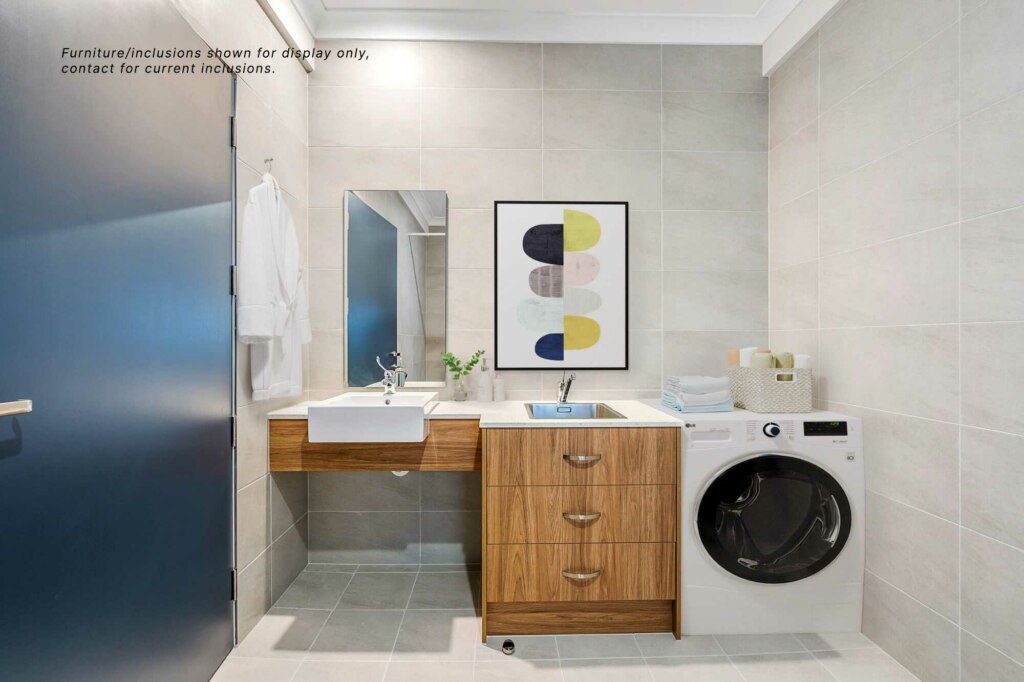 Modern bathroom in Inner Sydney with grey tiled walls, a wooden vanity, white sink, large mirror, front-load washing machine, and a contemporary abstract art piece above the sink.