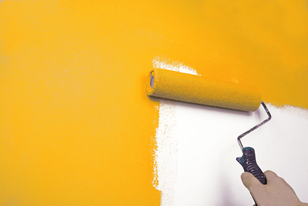 In North Gosford, a hand skillfully wields a paint roller, transforming a plain white wall into a vibrant canvas of bright yellow.