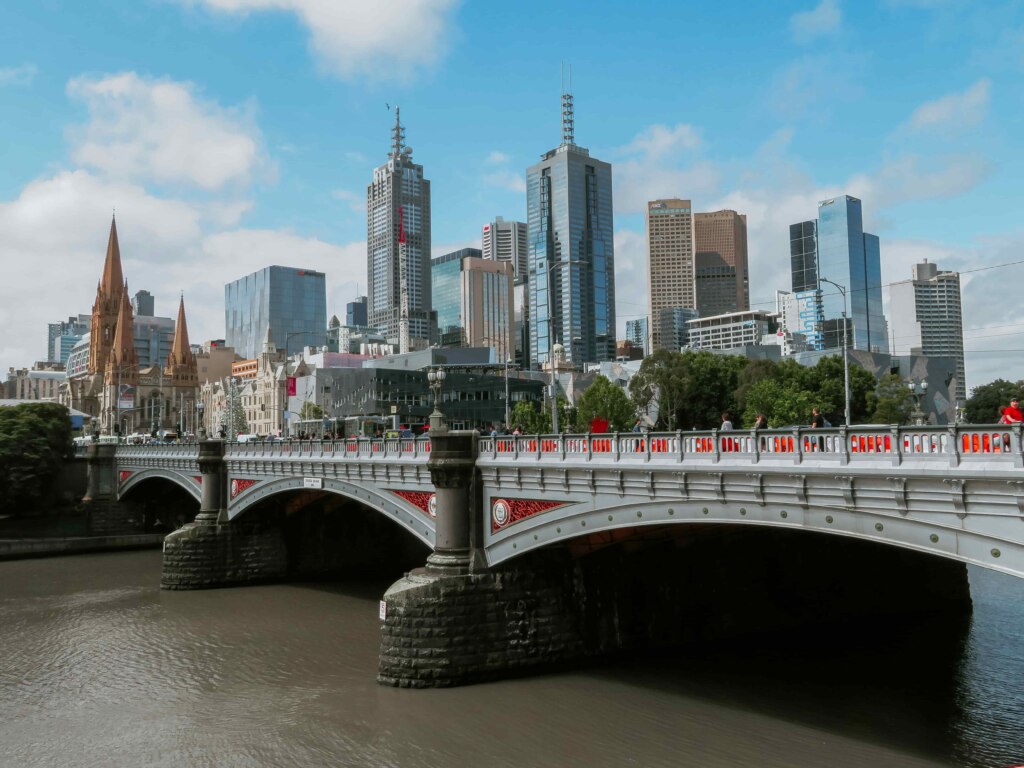 A accessible bridge over a river with a city skyline in the background.