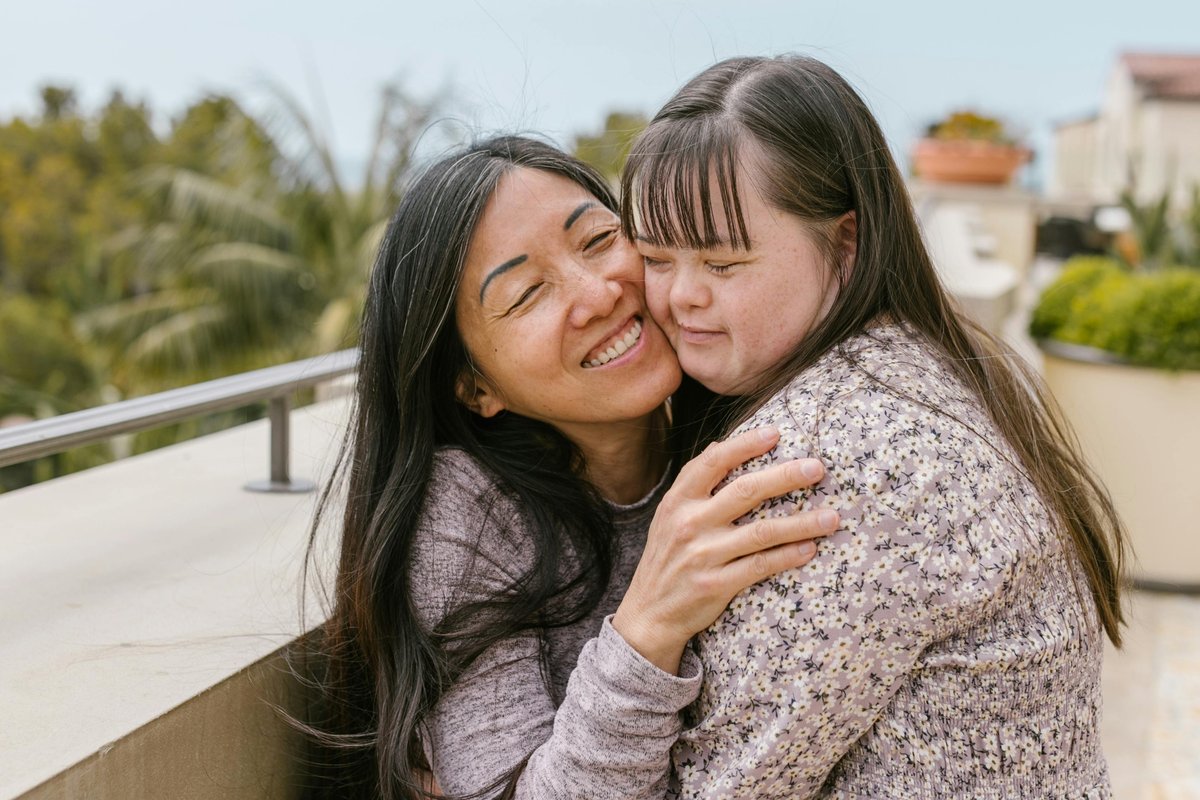 Loving mother warmly embracing her daughter with Down syndrome, showcasing happy family moments and inclusive disability support