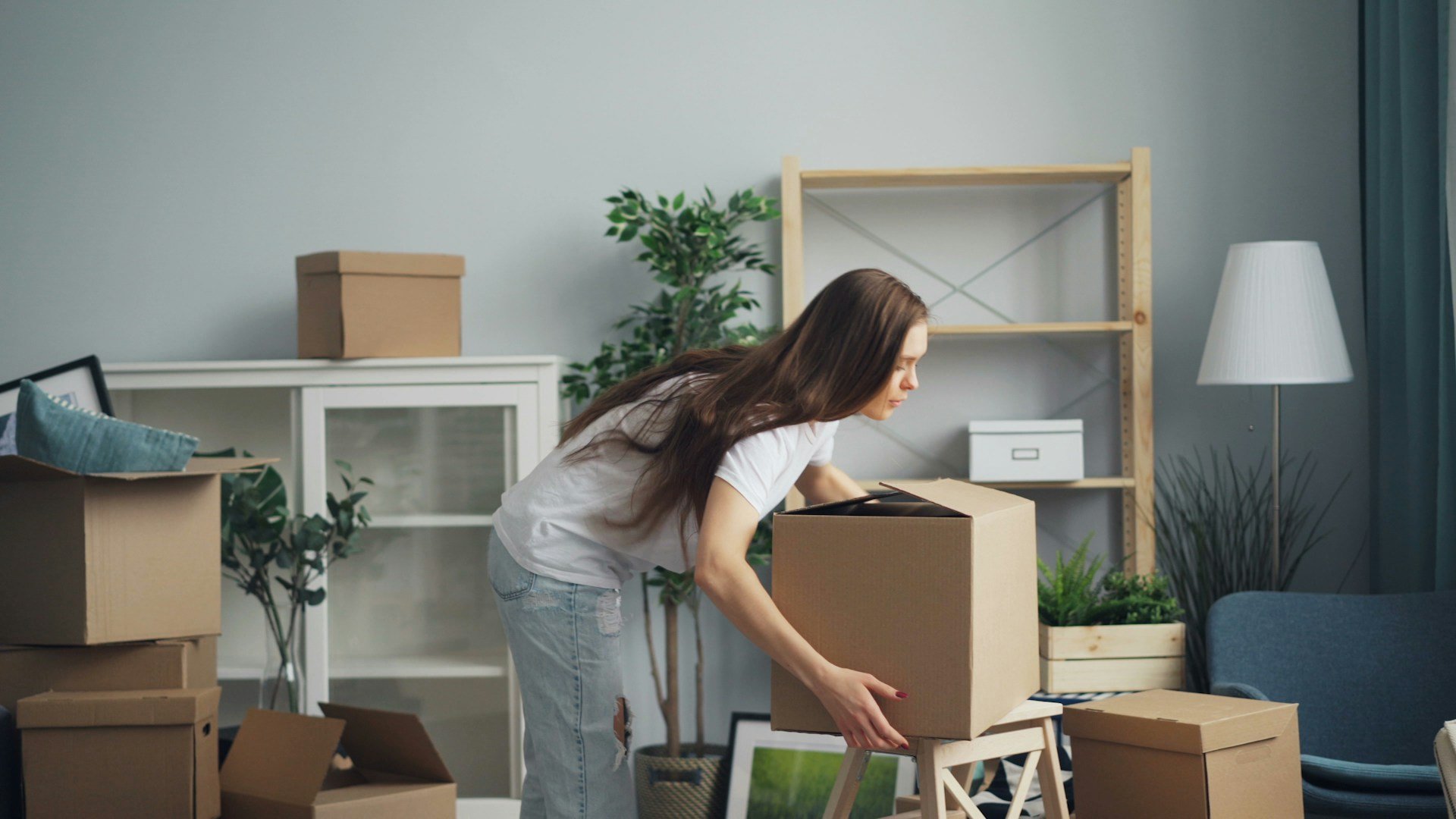 A woman packing boxes in a bright living room while moving into SDA
