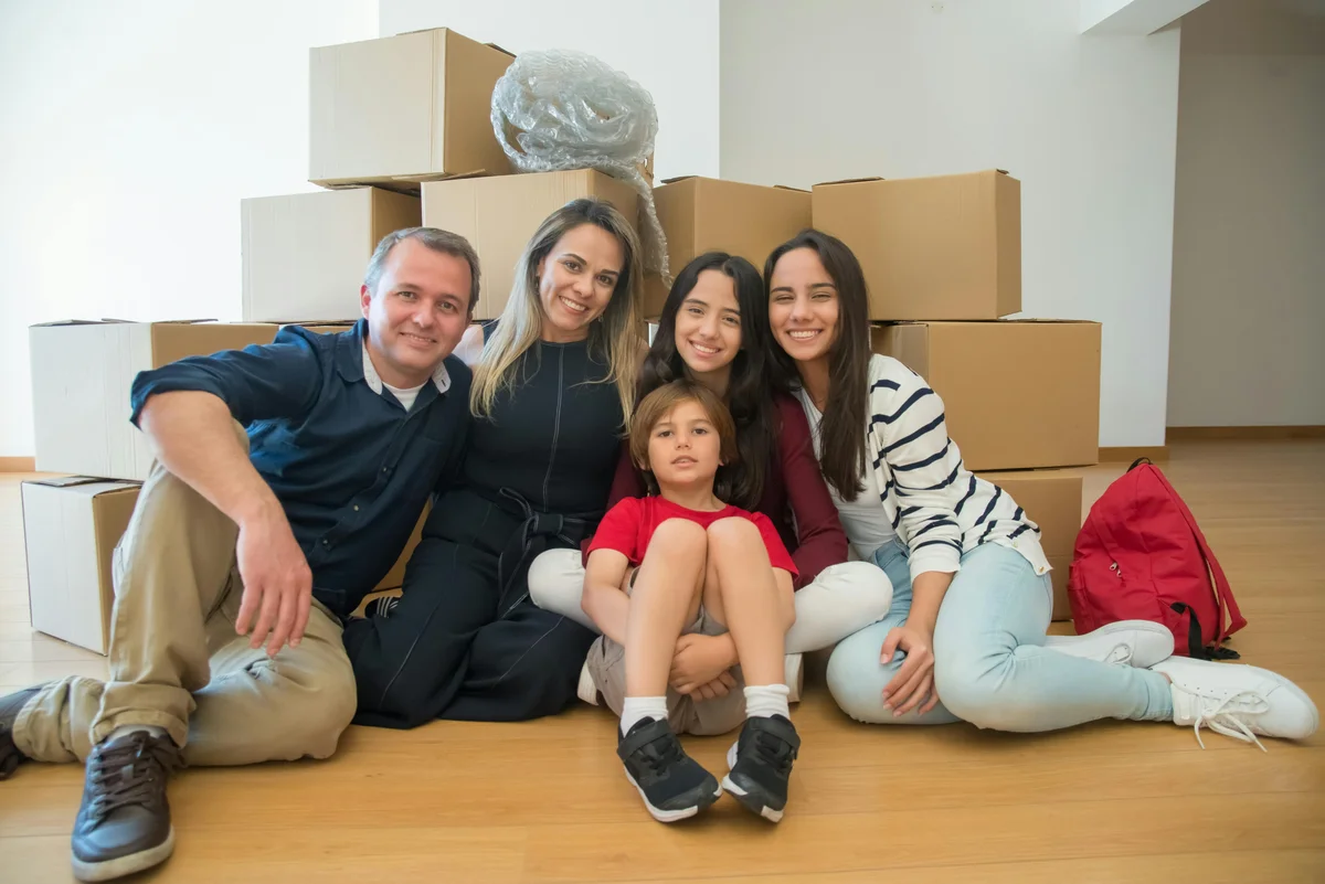 Joyful family with moving boxes in new SDA home representing successful NDIS housing placement