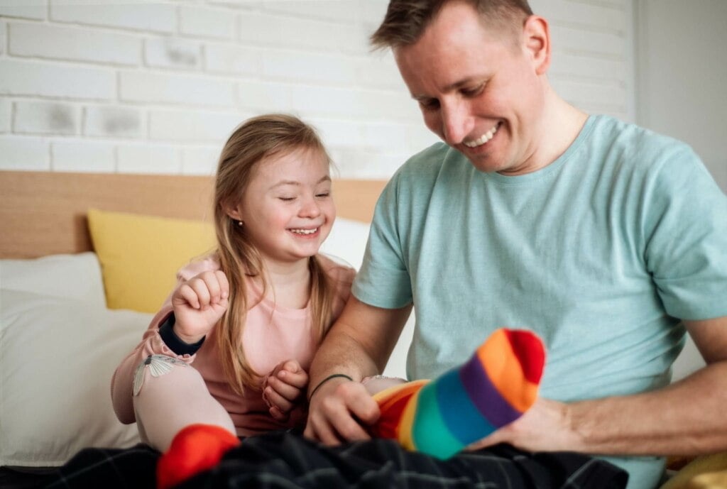 Father and daughter enjoying a playful moment with socks in bed, creating a memorable bonding experience.